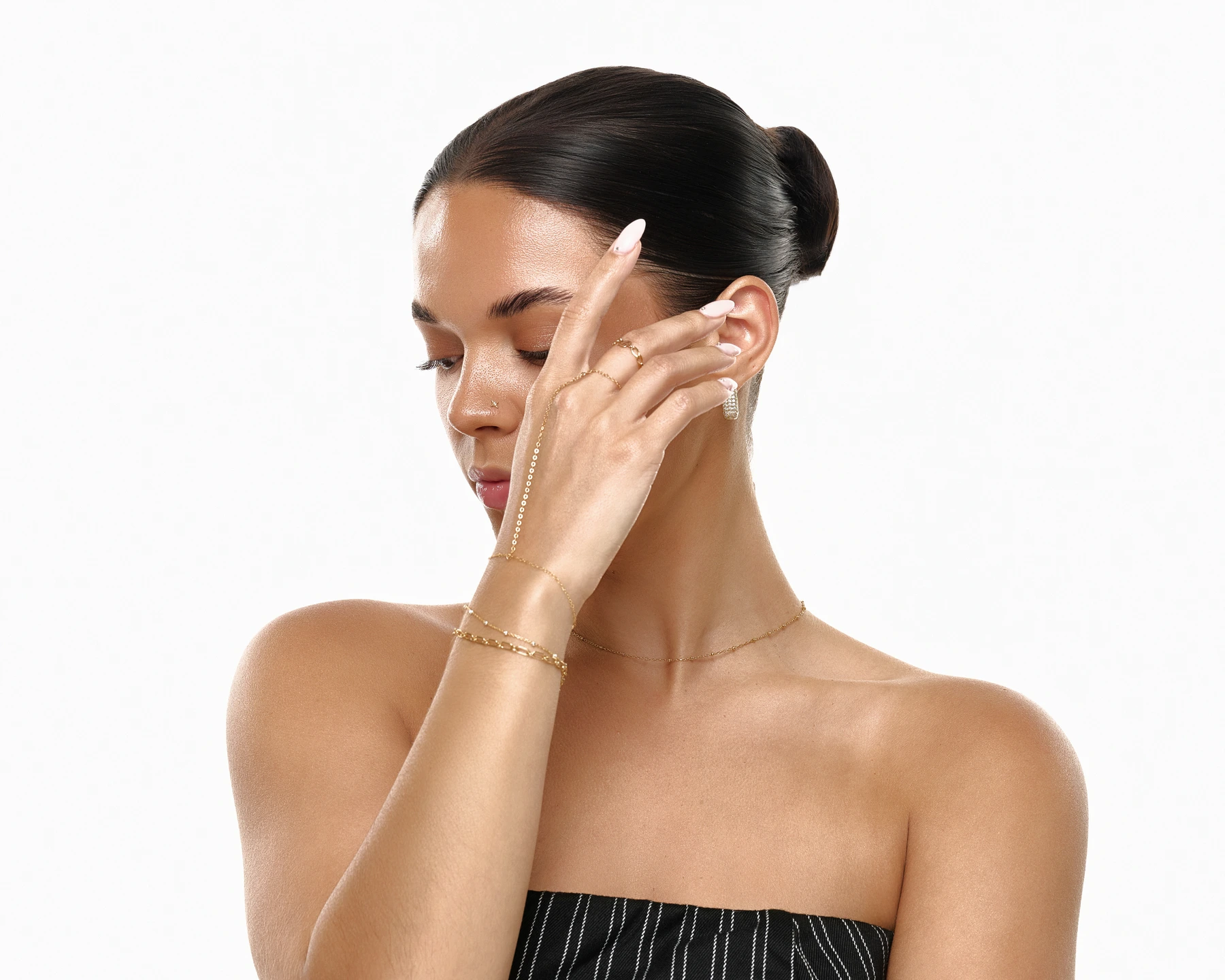 Gold hand-chain jewelry, rings, and earrings styled on a model against white