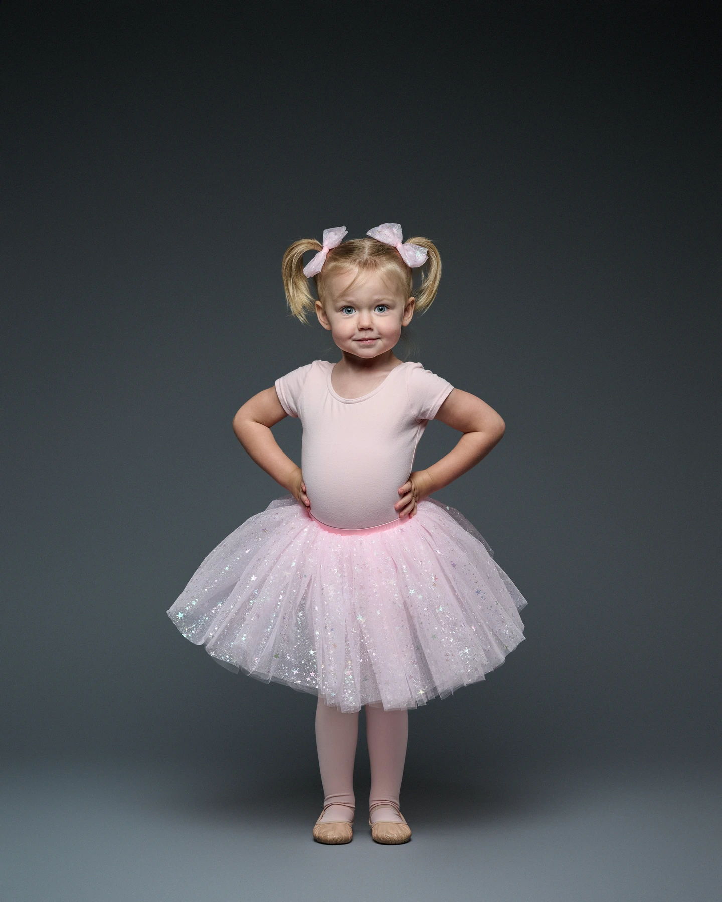 Child modeling a pink tutu with matching pink hair bows