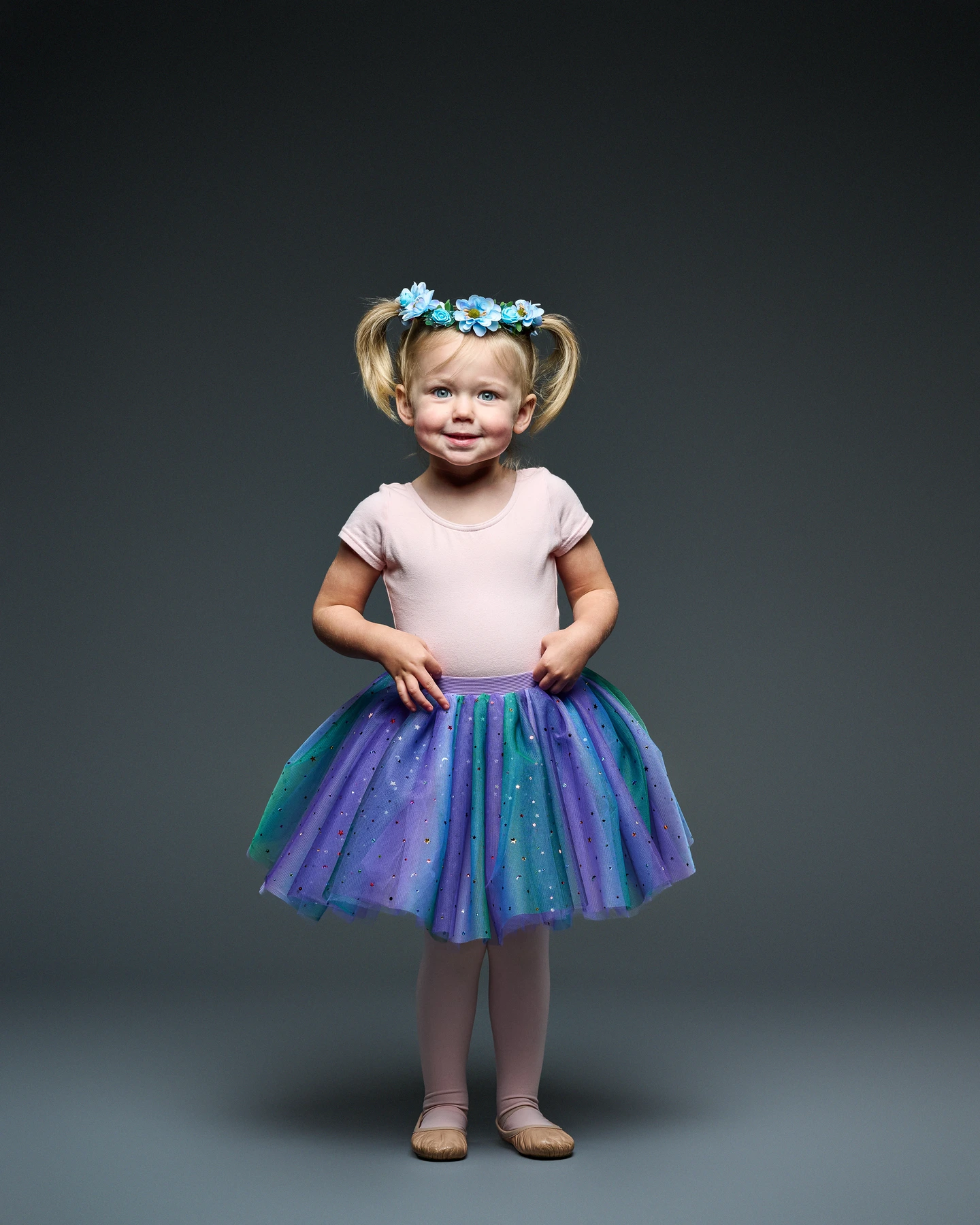 Child modeling a purple and teal tutu with a blue floral headband