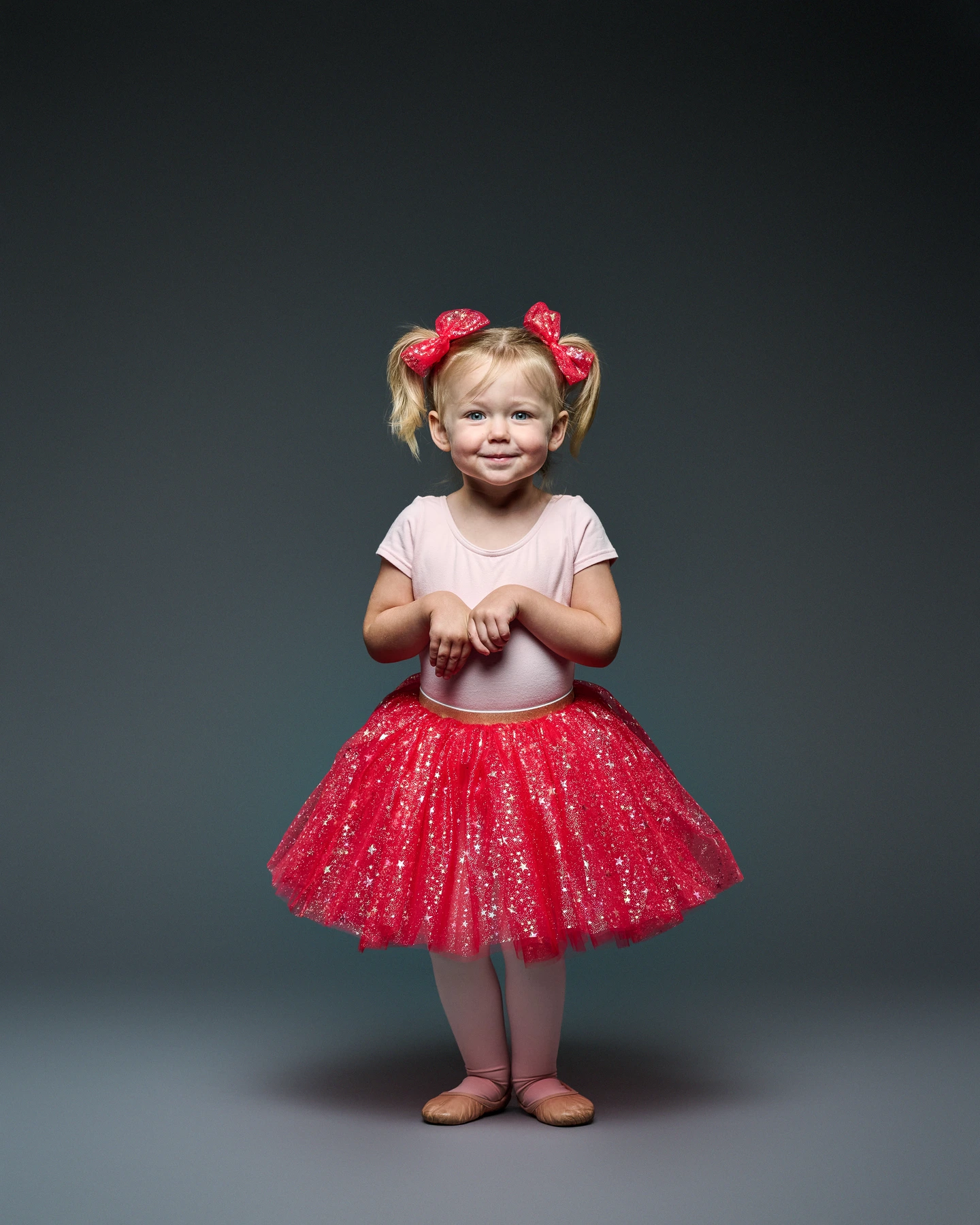 Child modeling a red tutu with matching red hair bows