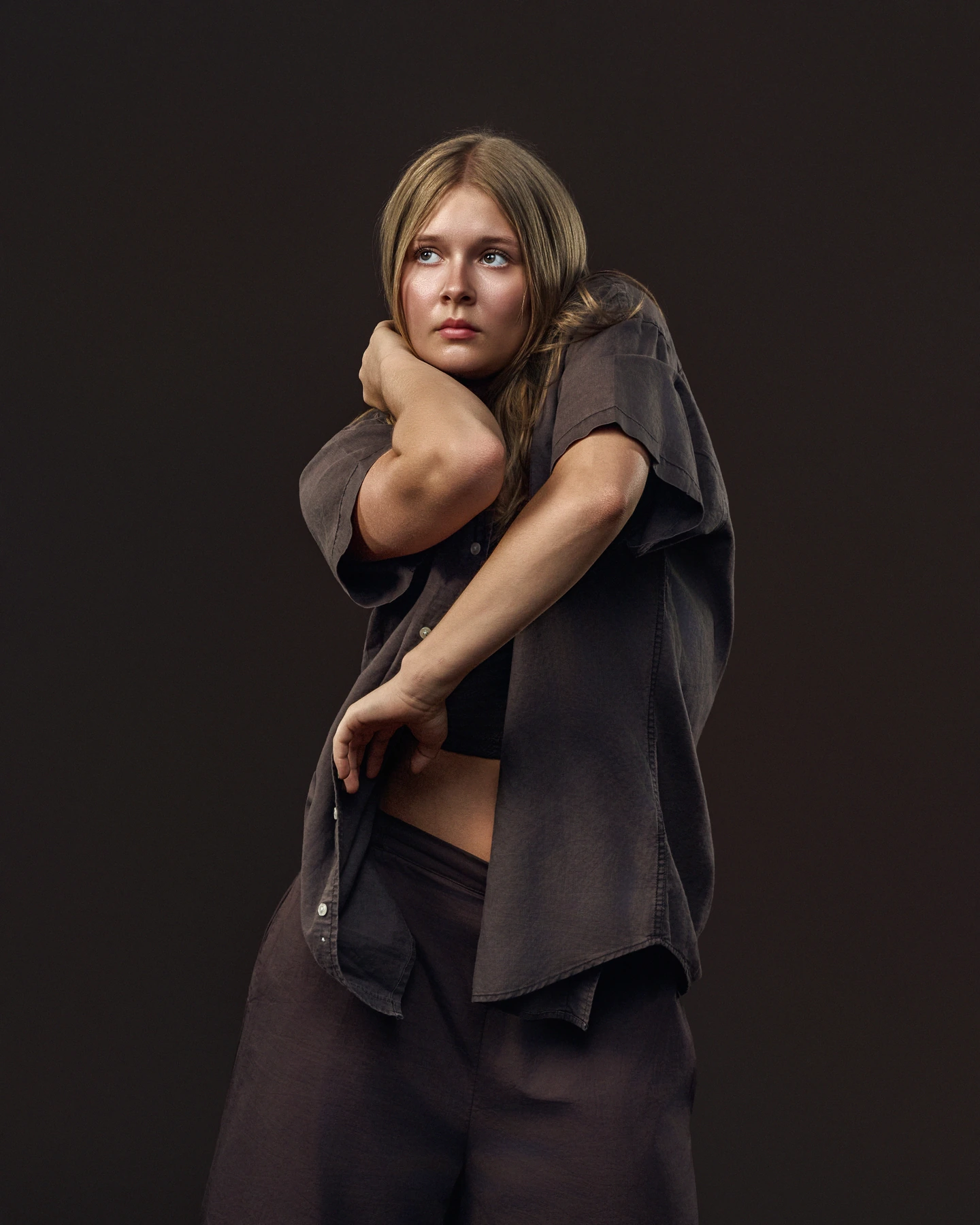 Expressive dance portrait in a charcoal shirt against a dark backdrop