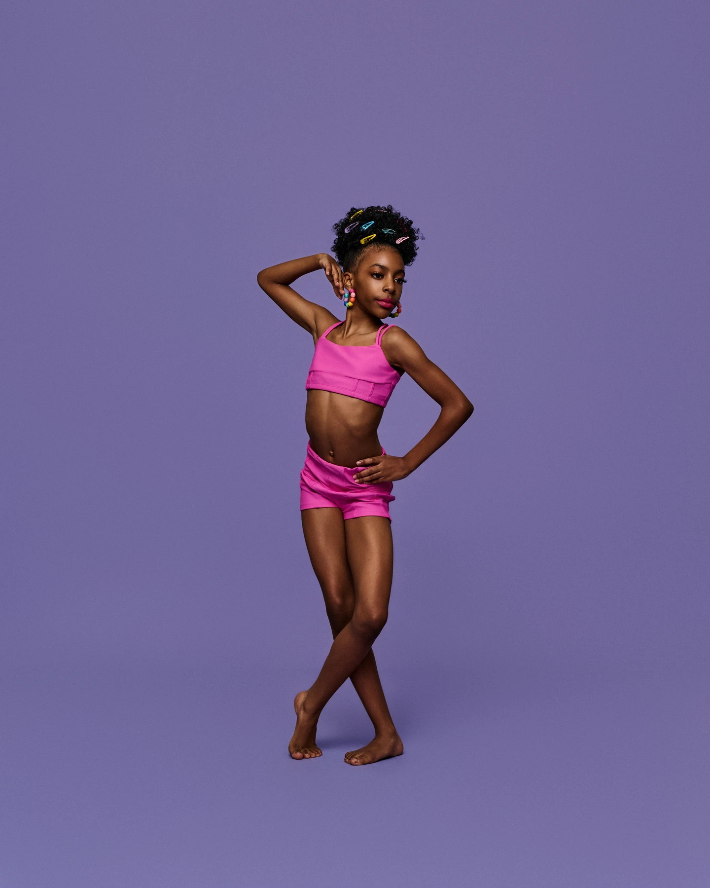 Dancer in bright pink with colorful hair clips against lavender
