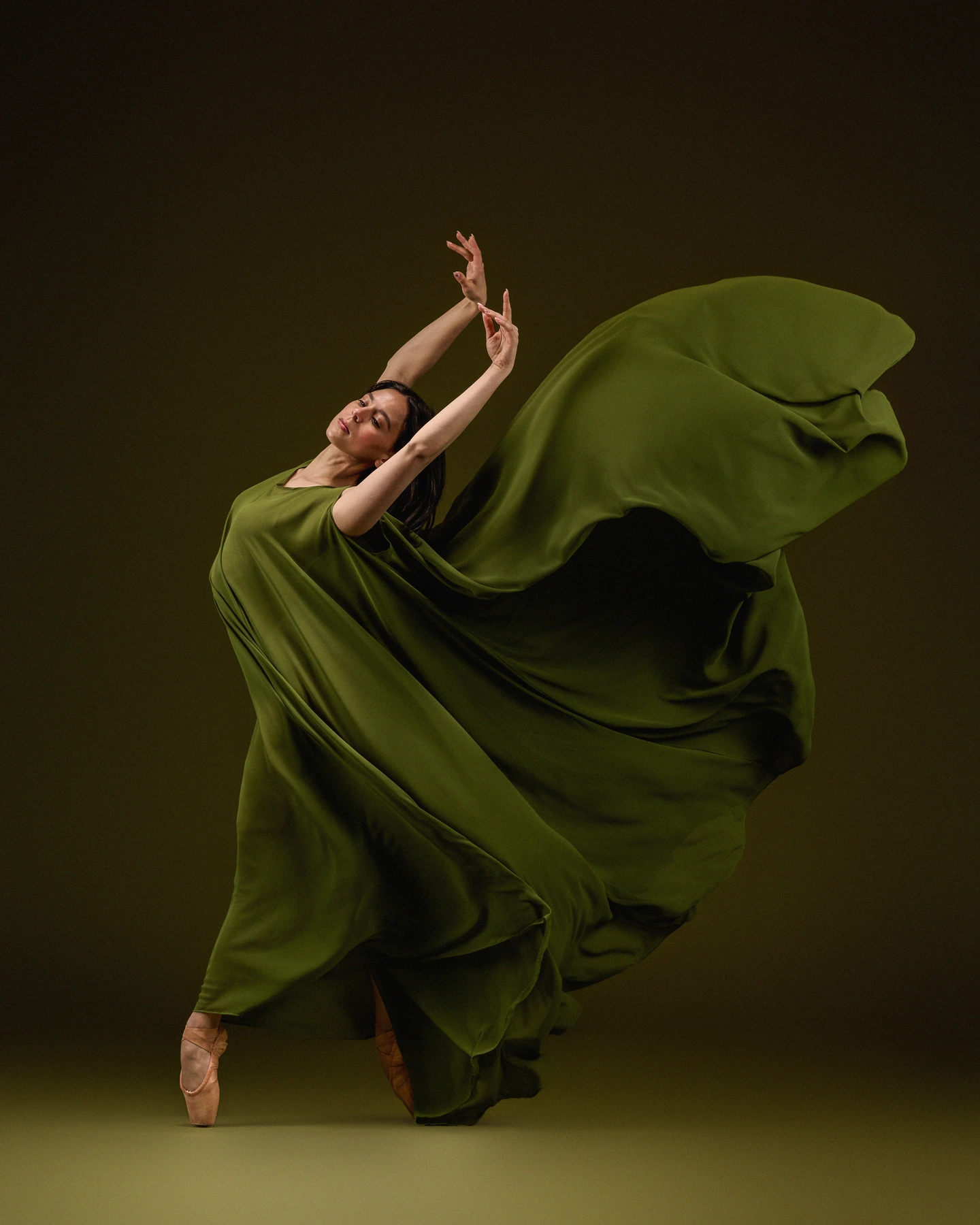Ballerina wrapped in sweeping olive fabric against an olive backdrop