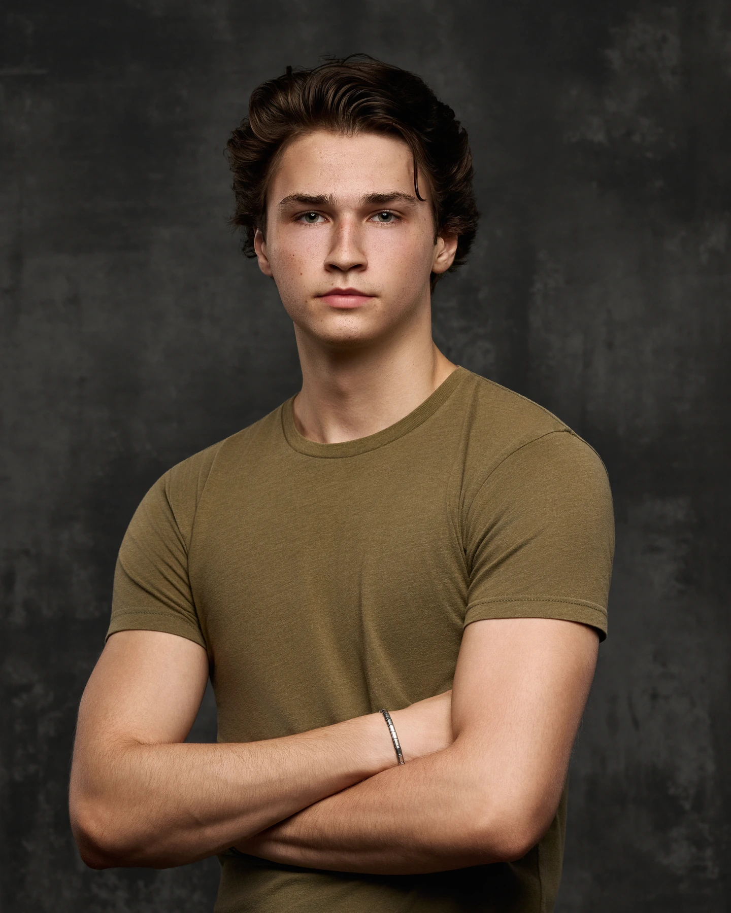 Headshot in an olive shirt against textured charcoal gray