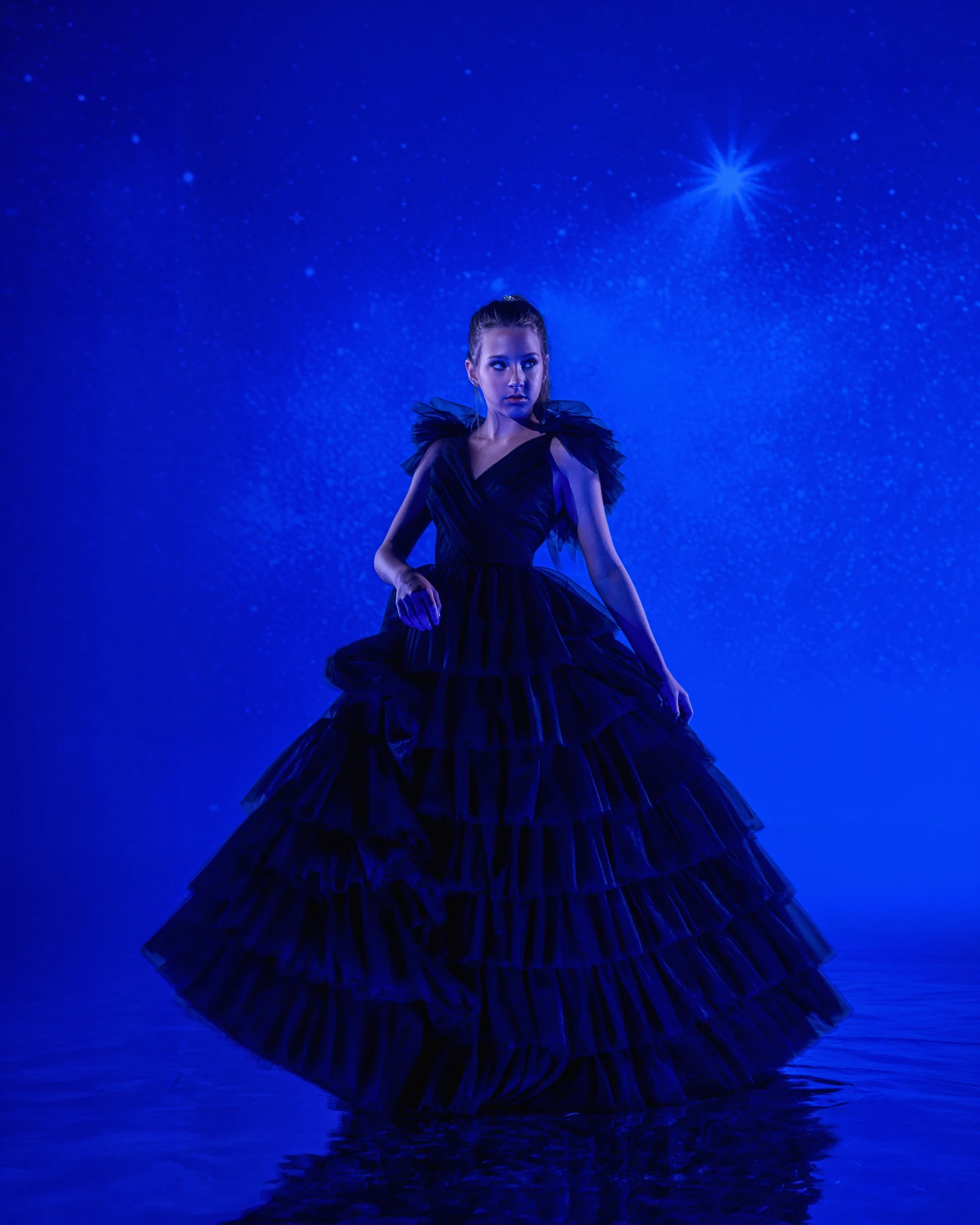 Portrait in a long black gown beneath blue projected stars