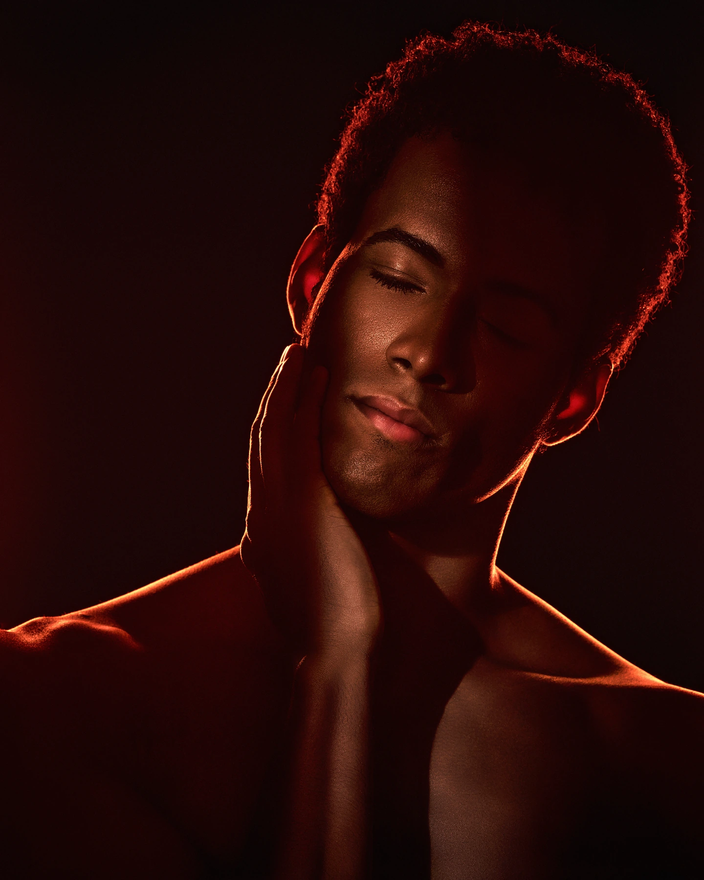 Close portrait with eyes closed and warm red rim lighting