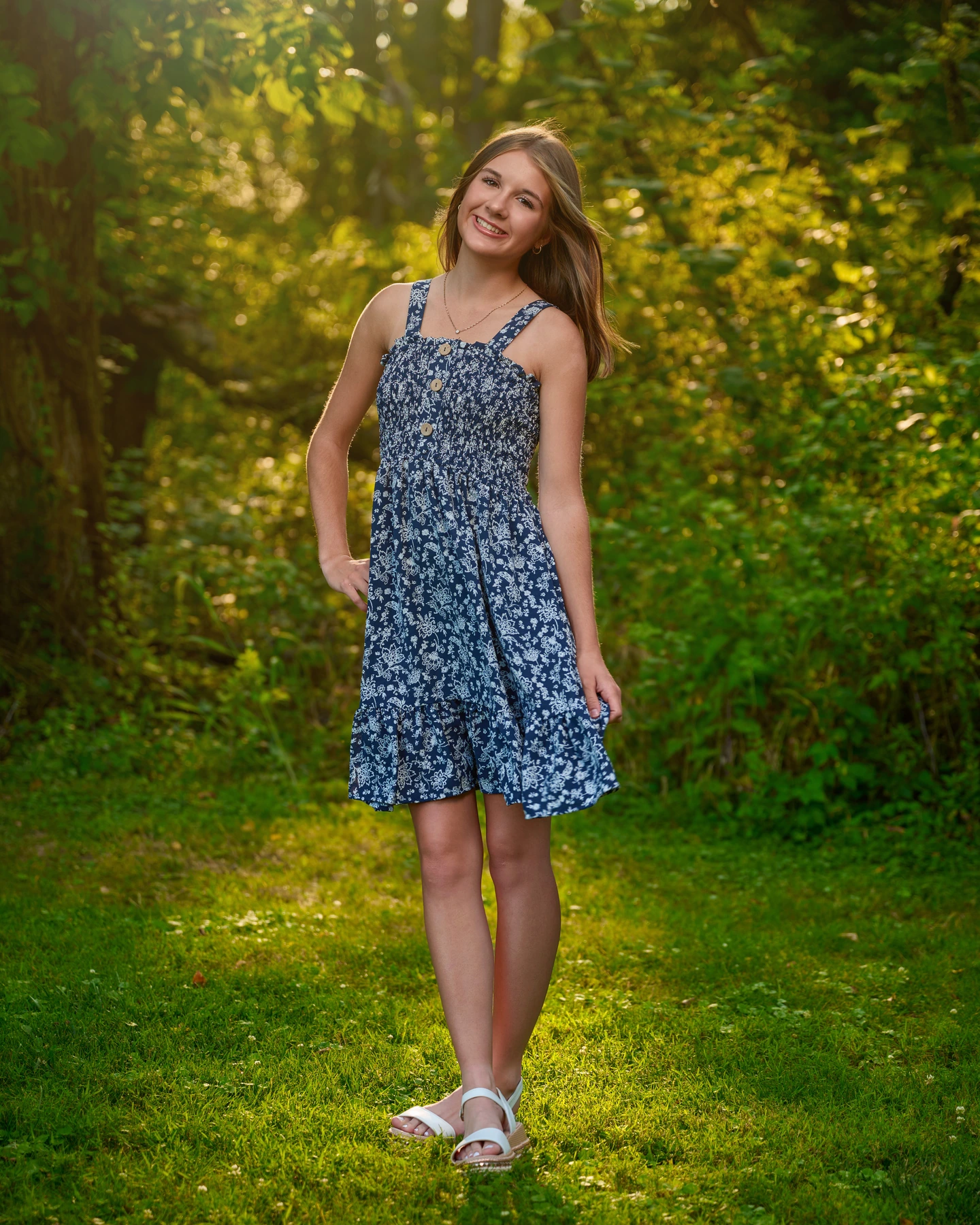 Outdoor portrait in a navy floral dress surrounded by sunlit greenery