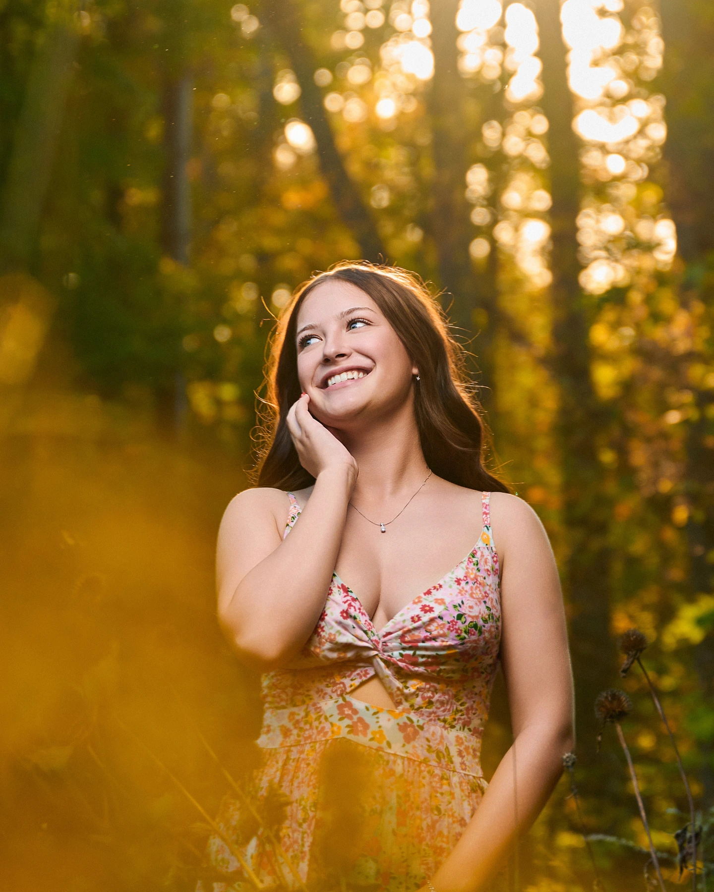 Smiling outdoor portrait framed by golden sunlight and foliage
