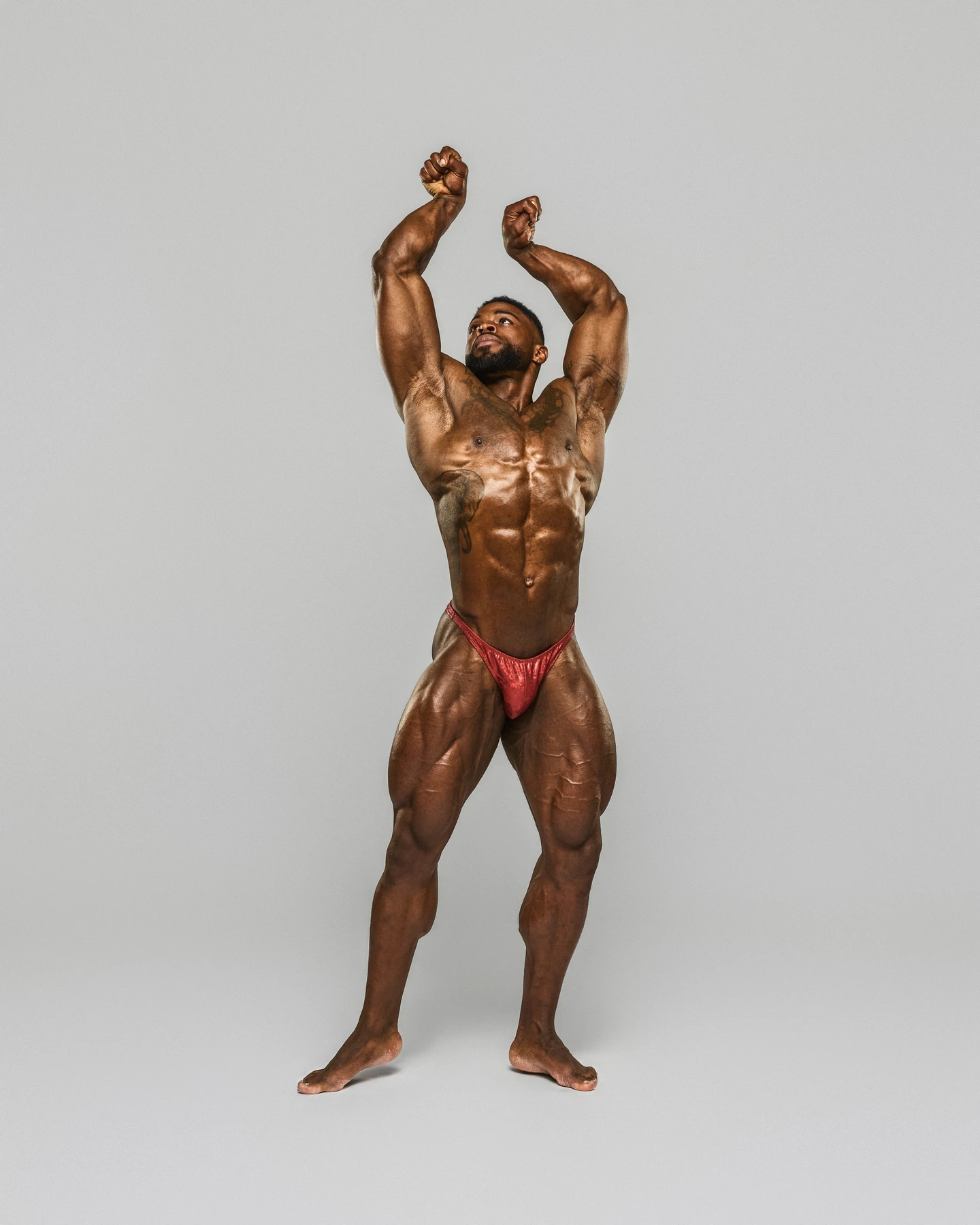 Bodybuilding portrait with raised arms against light gray
