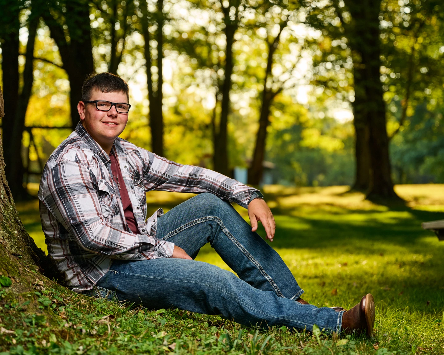 Outdoor portrait wearing glasses and a plaid shirt beside a tree